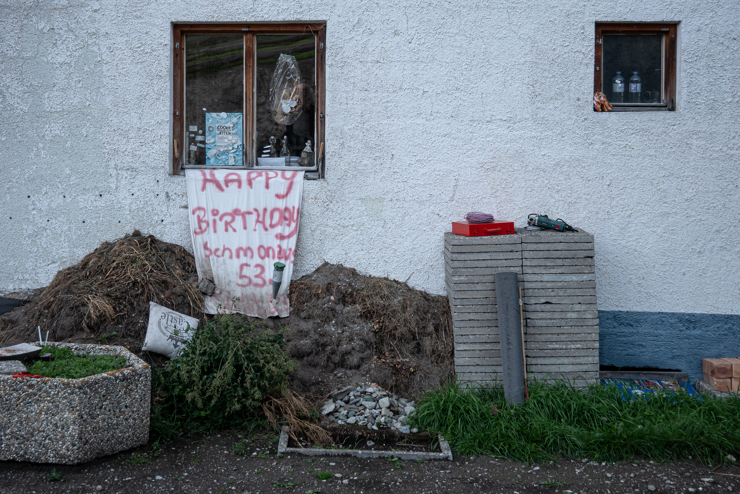 „Happy Birthday“-Transparent am Bauernhaus, davor der Misthaufen